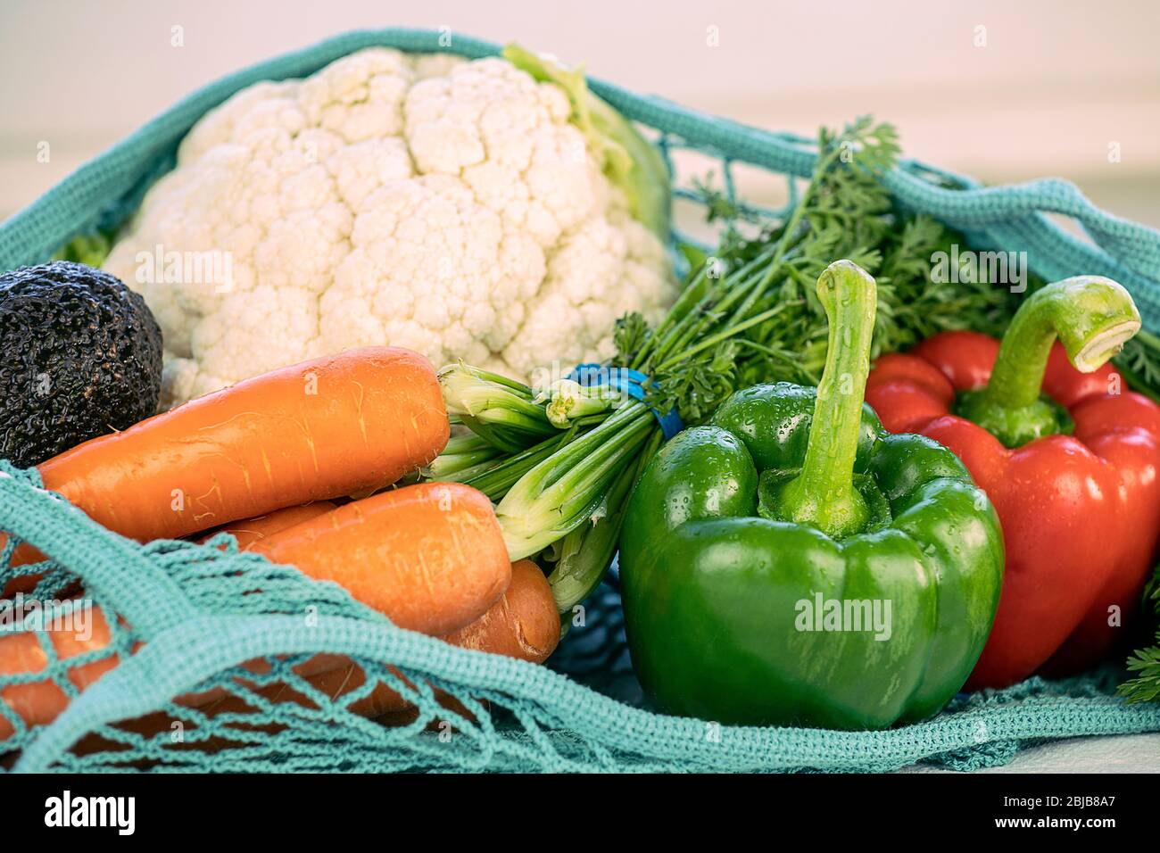 Close up of fresh produce in a blue fishnet knitted, Reusable, sustainable, eco friendly, earth day, no plastic concept. Various vegetables: peppers, Stock Photo