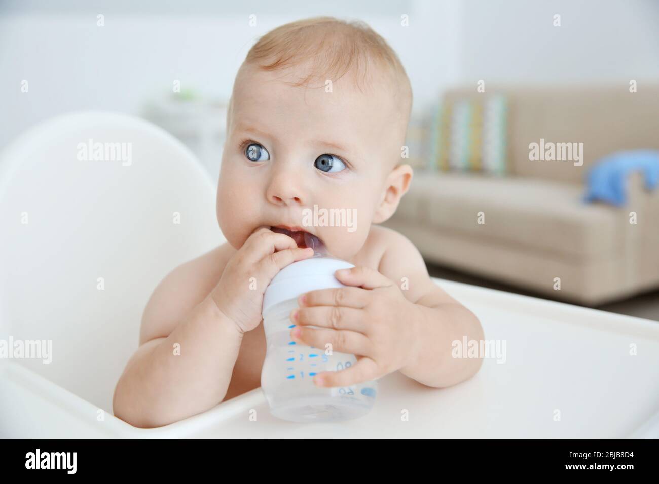 Little baby drinking water from bottle indoors Stock Photo Alamy