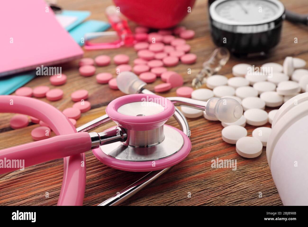 Pink Medical Instrument Pink stethoscope, pills and other medical equipment on wooden ...