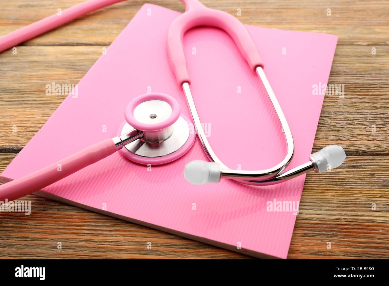 Pink stethoscope and copybook on wooden background Stock Photo Alamy