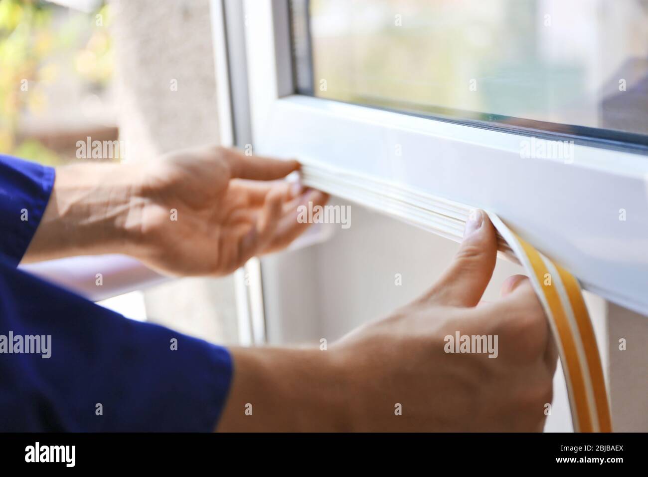 Construction worker putting sealing foam tape on window in house Stock Photo