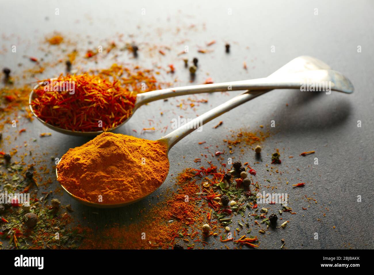 Spices in metal spoons on table Stock Photo