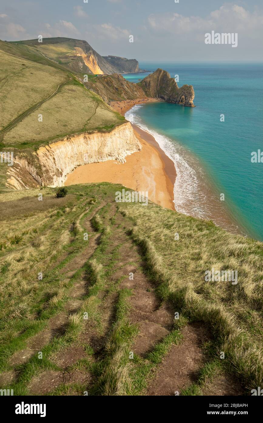 A high up view of the famous limestone arch Durdle Door and golden sand beach from the South West Coastal Path running on top of the near by cliffs, L Stock Photo