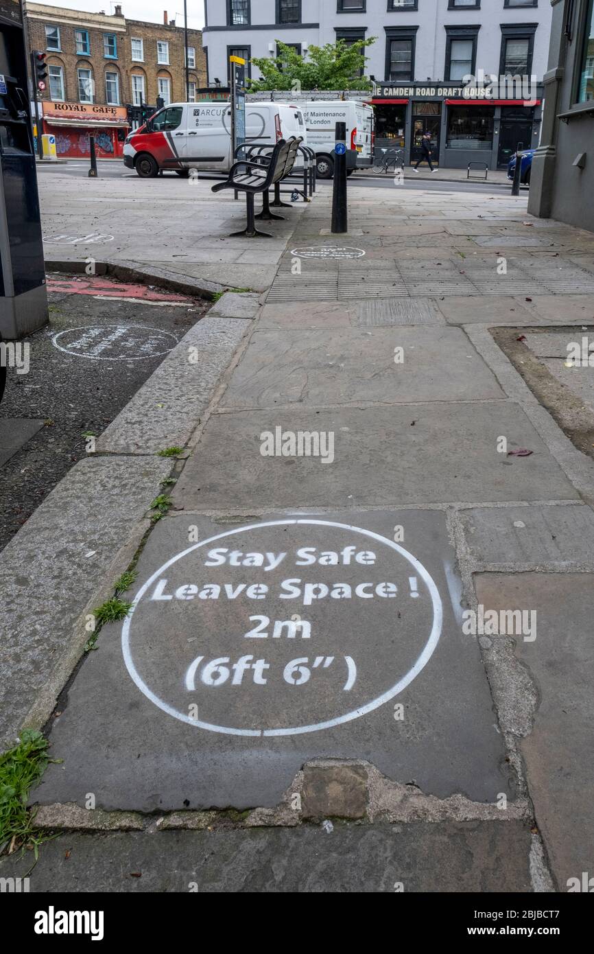 Lockdown London, April 29th 2020: spray painted pavement graffiti reminding people of the 2 metre social distance required during lockdown in London Stock Photo