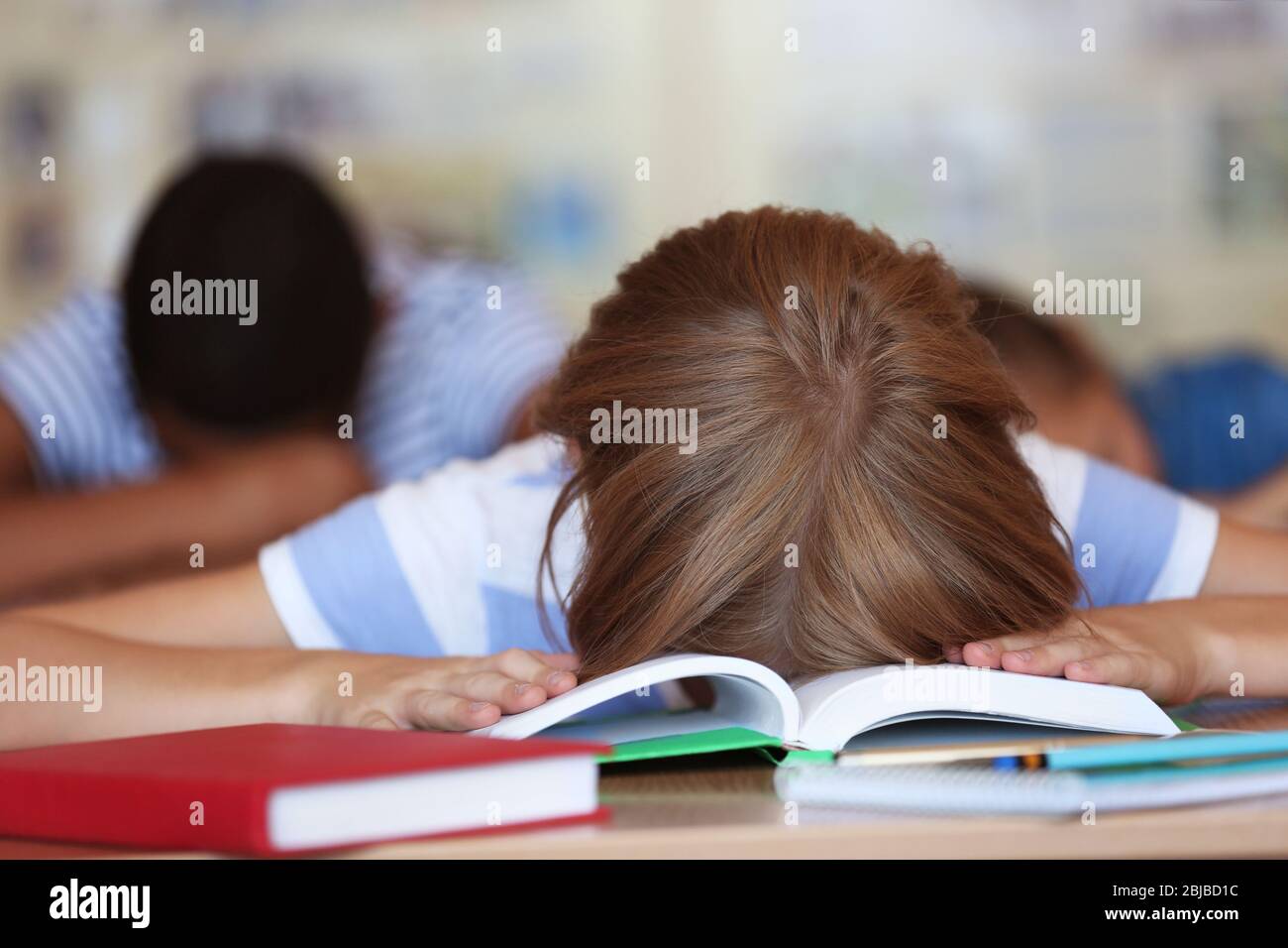 Tired schoolgirl in classroom on lesson Stock Photo