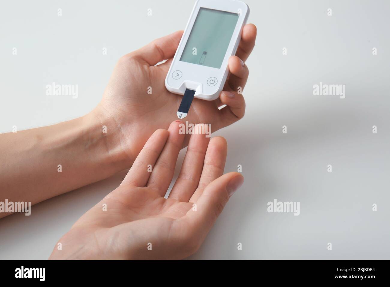 Woman checking blood sugar level by and test stripe at home