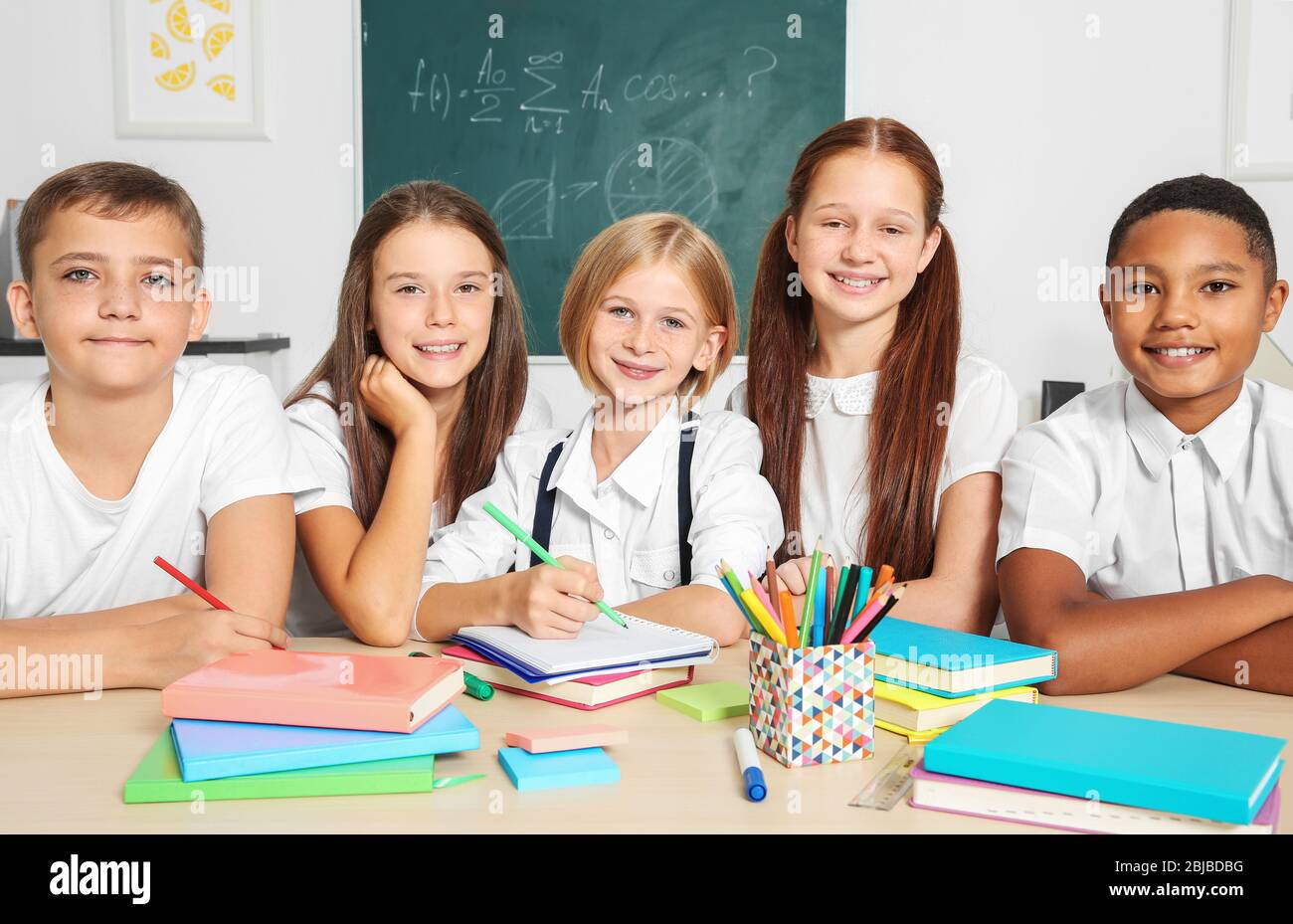 Schoolchildren drawing while sitting at table in classroom Stock Photo