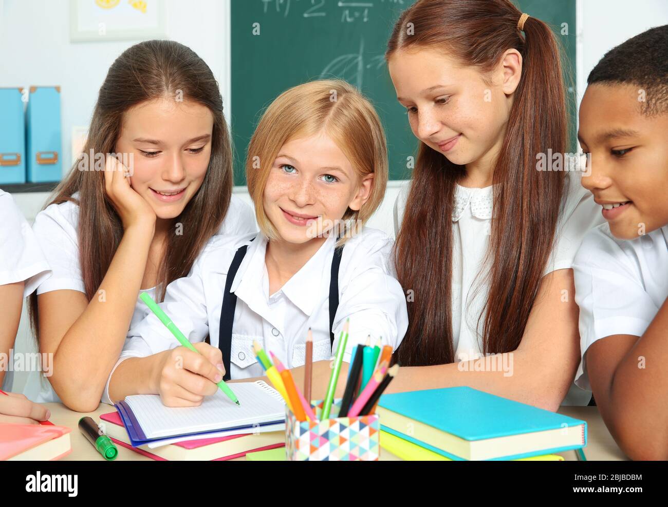 Schoolchildren drawing while sitting at table in classroom Stock Photo