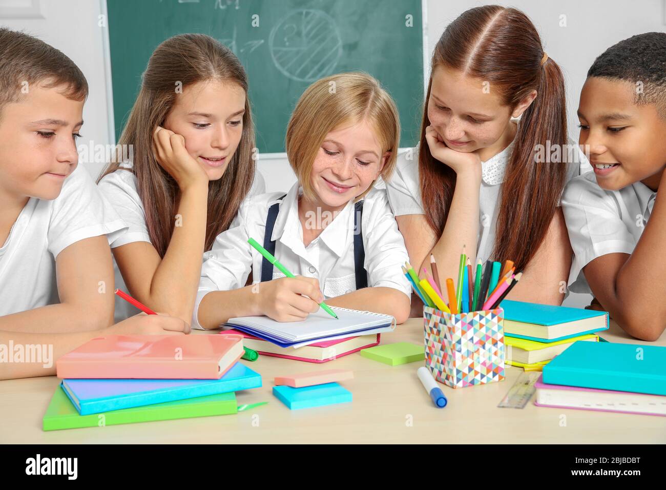 Schoolchildren drawing while sitting at table in classroom Stock Photo