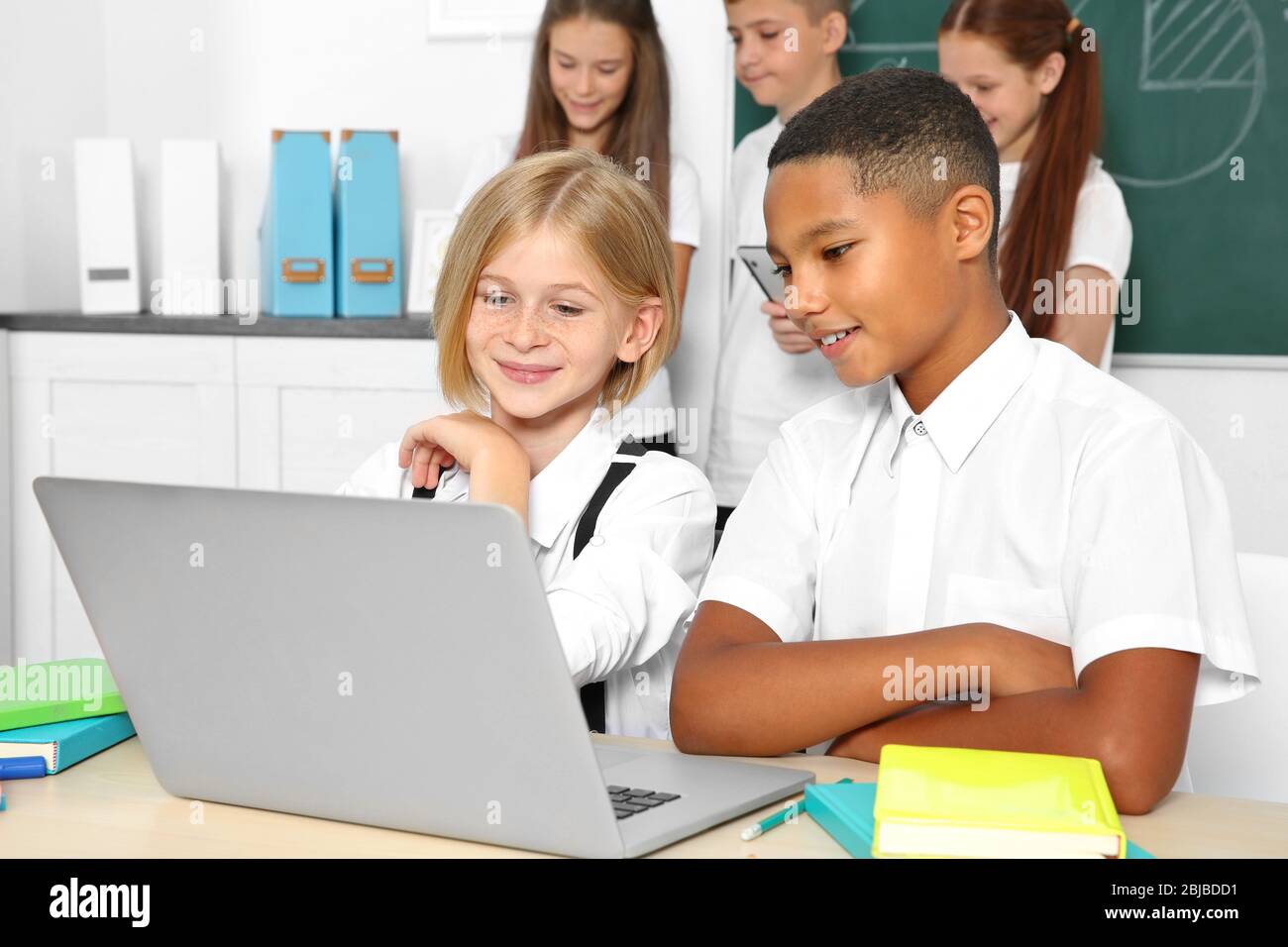 Schoolchildren sitting in classroom with laptop Stock Photo - Alamy