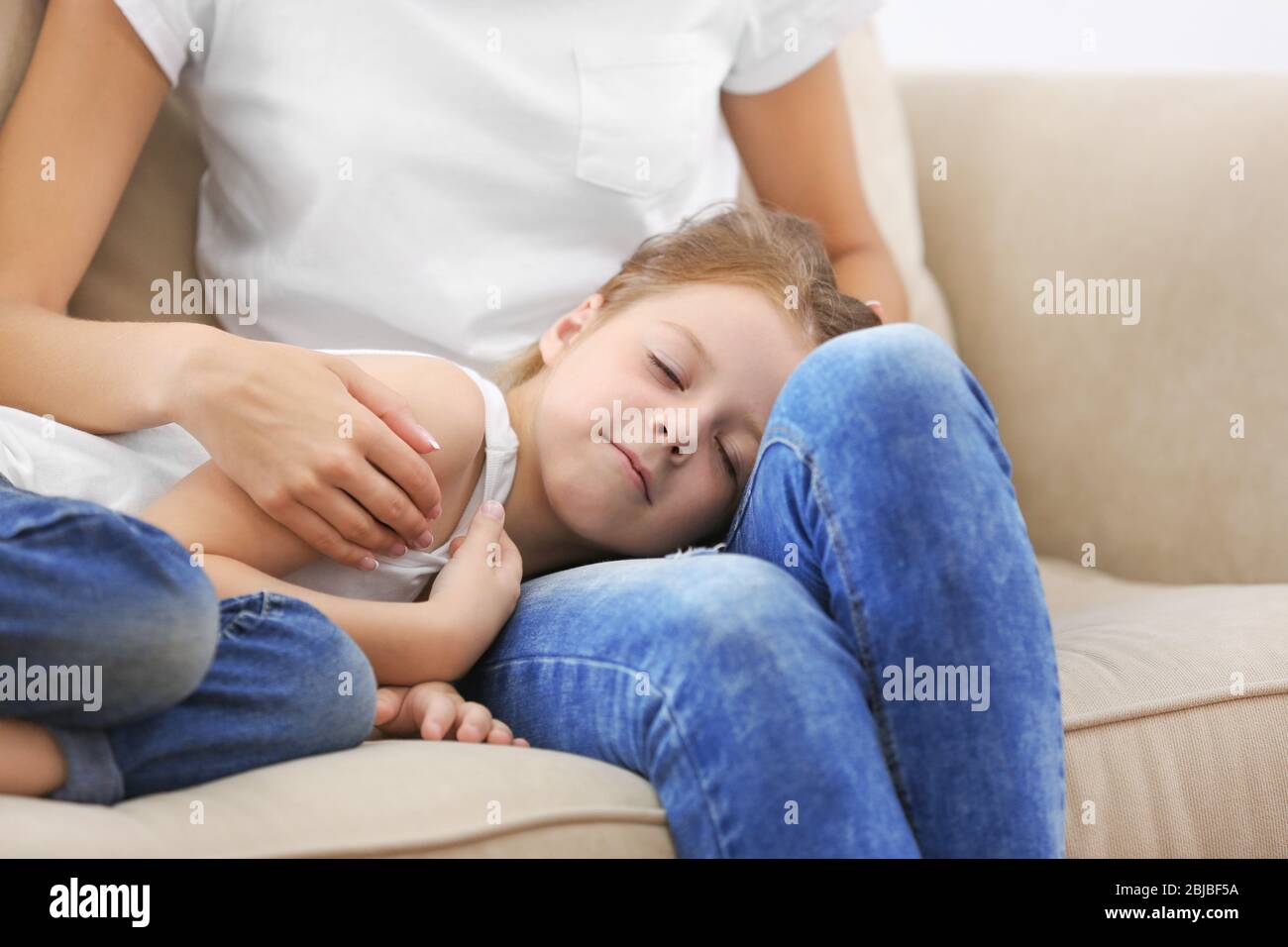 Cute girl lying on mothers knees at home Stock Photo