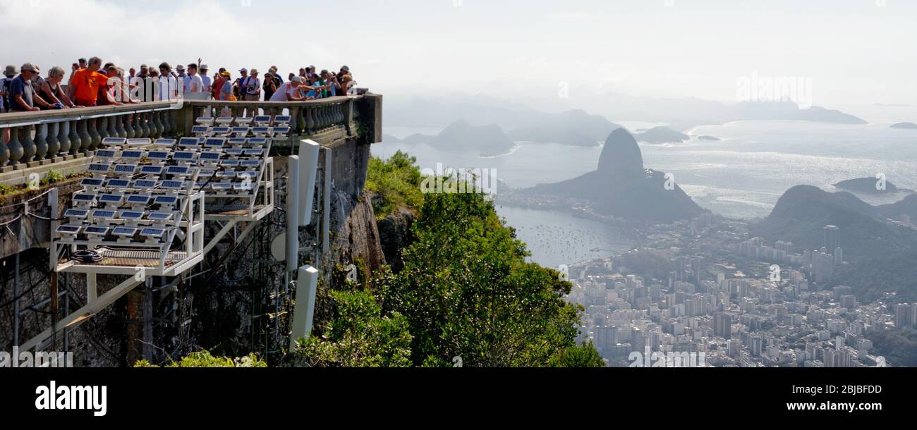 Tourists on the viewing areas of Christ the Redeemer state on Corcovado mountain, looking across Rio De Janeiro, Brazil Stock Photo