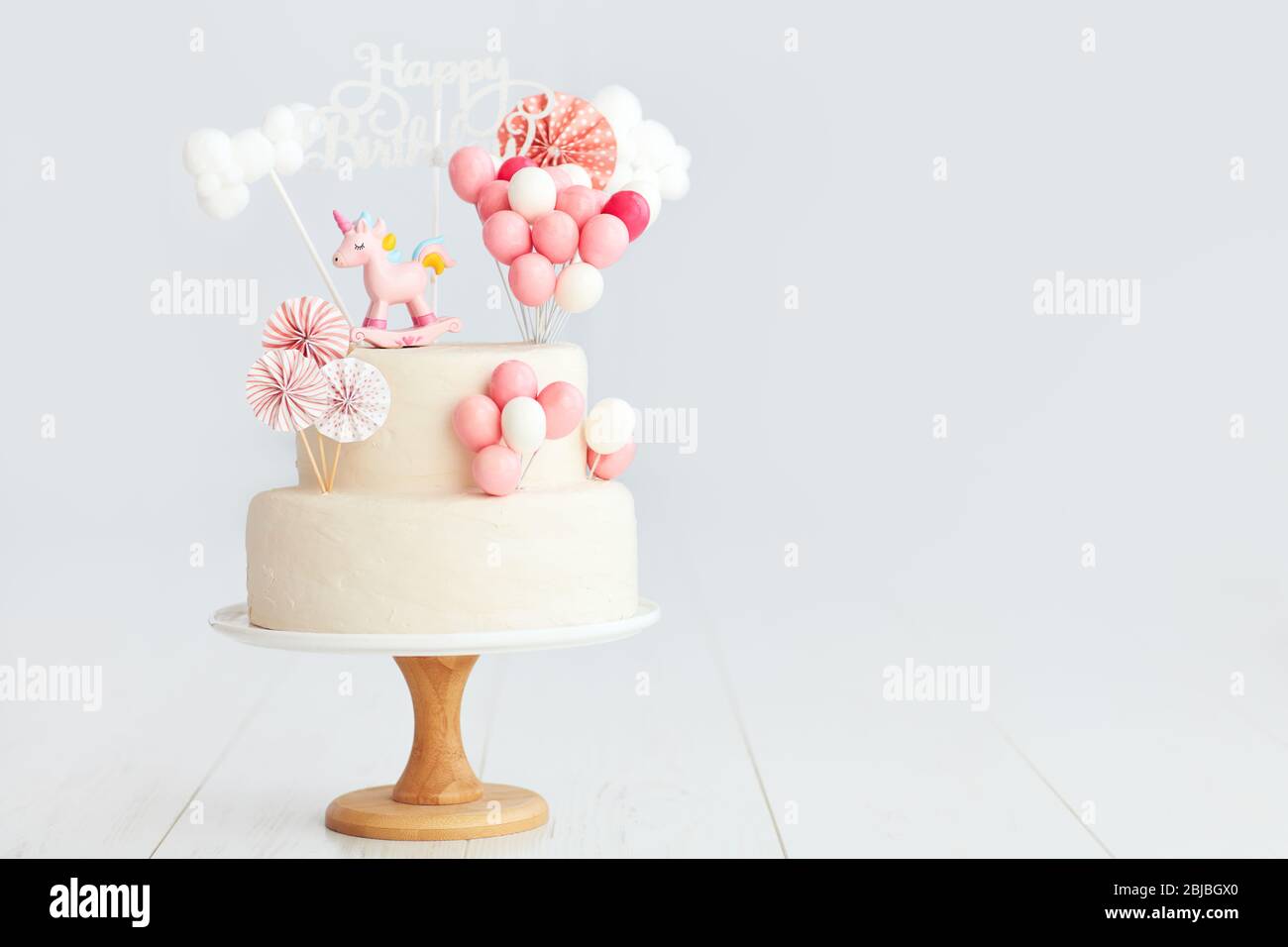 baby girl birthday cake with unicorn and balloons Stock Photo