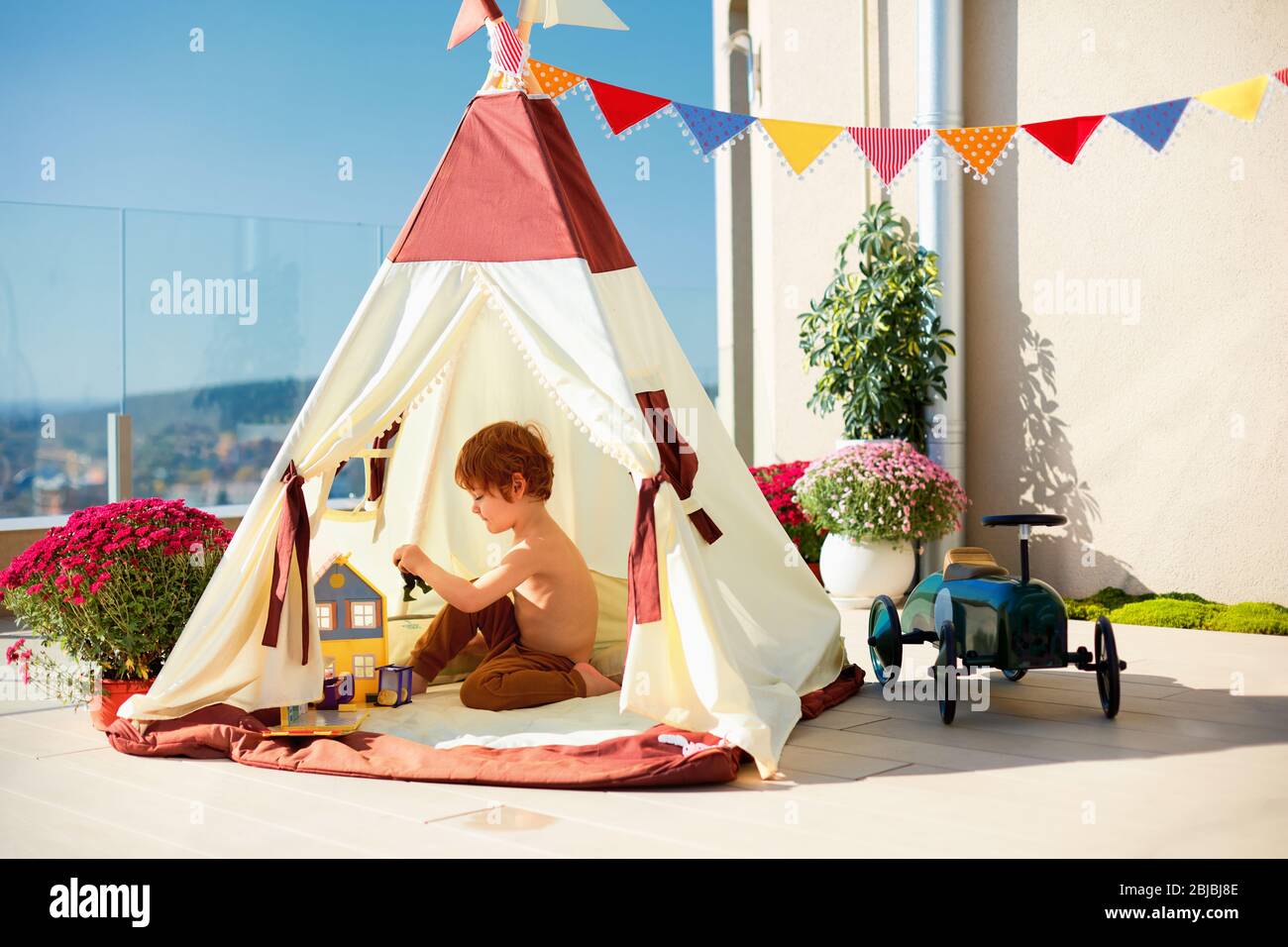 cute toddler kid, boy playing peacefully inside of a teepee tent on sunny  rooftop patio Stock Photo - Alamy