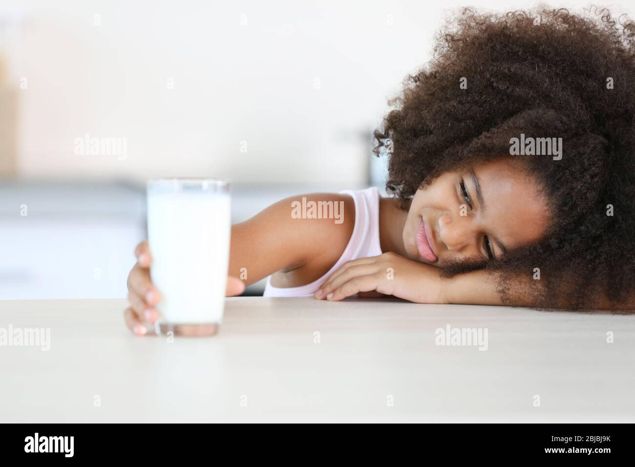 Cute African-American girl does not want to drinking milk for breakfast Stock Photo