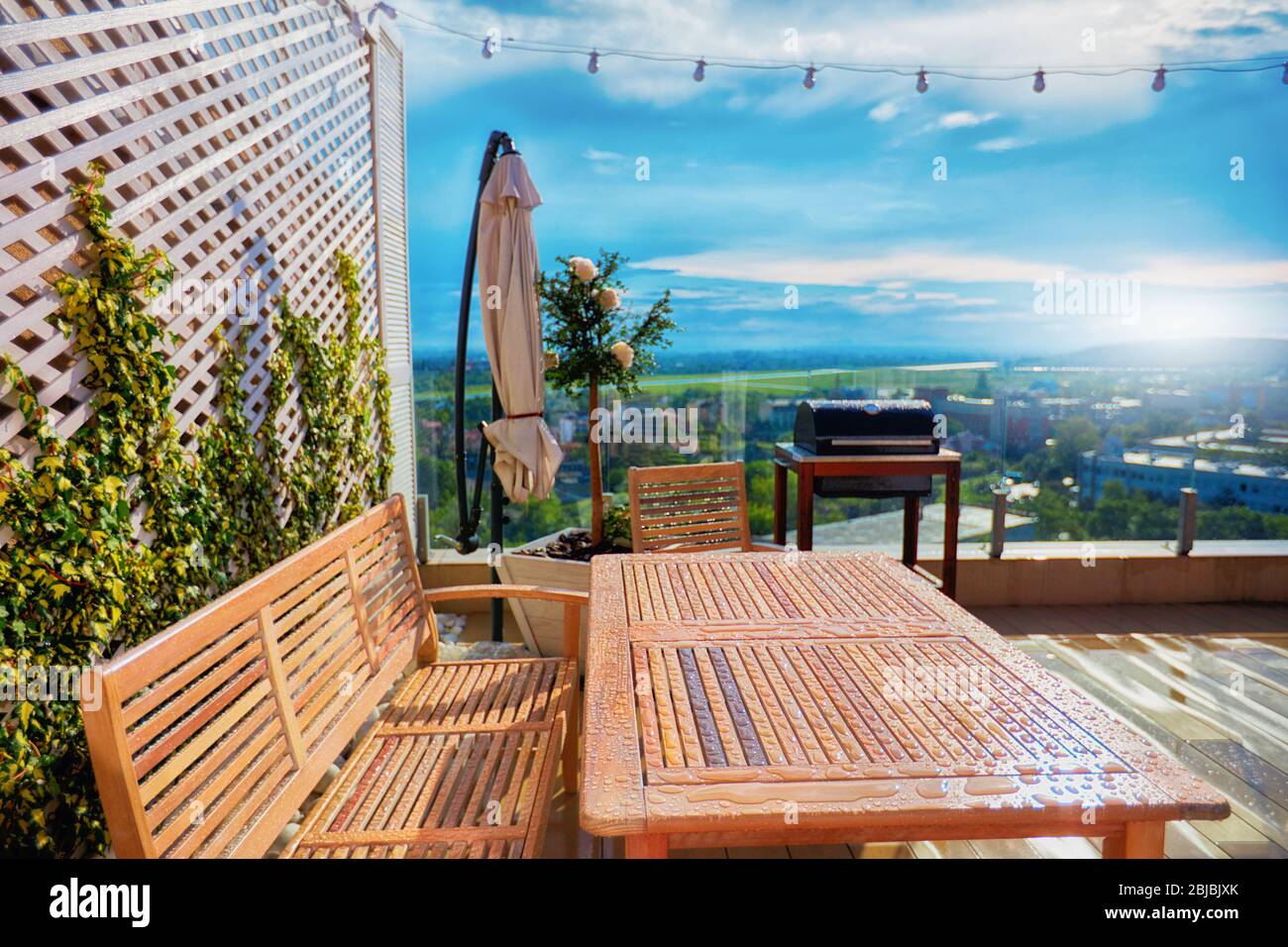 wooden furniture covered with water drops after warm spring rain at rooftop patio Stock Photo