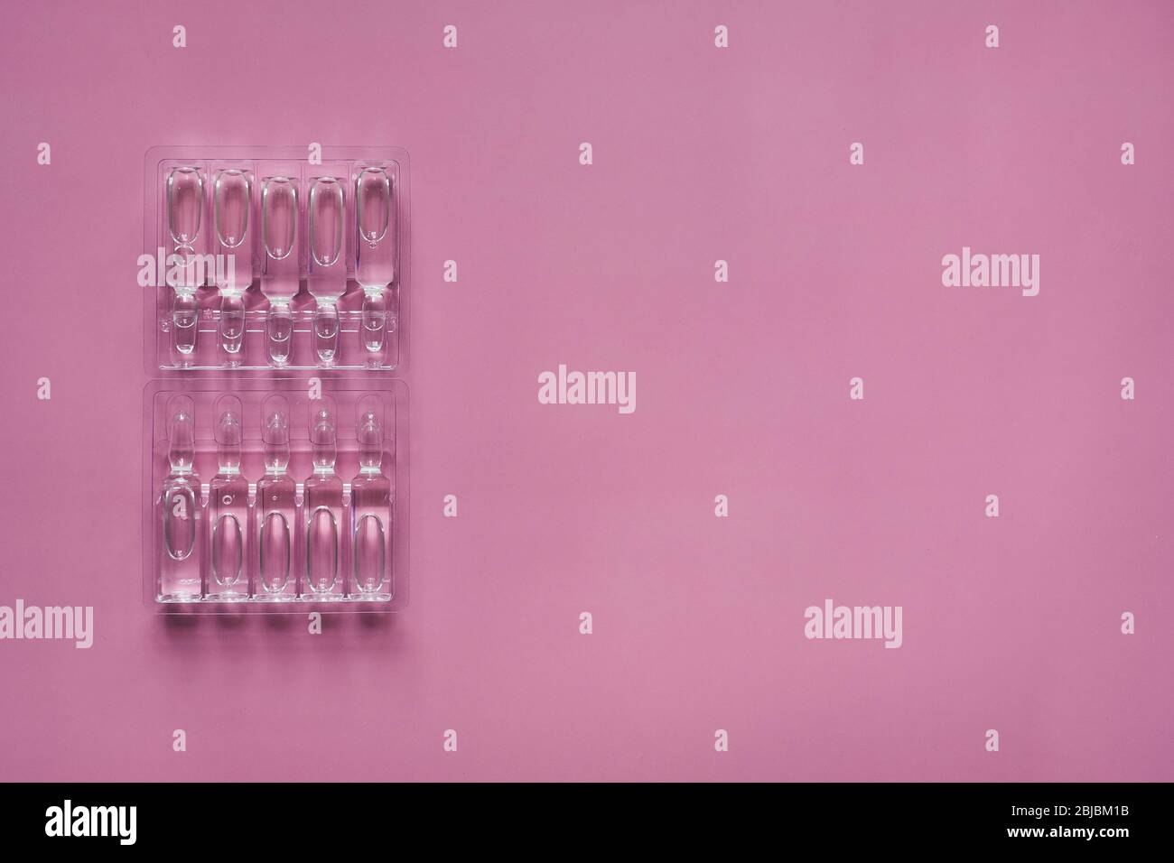 Ampoules with medicine on pink background. Pharmaceutical, cure. Stock Photo