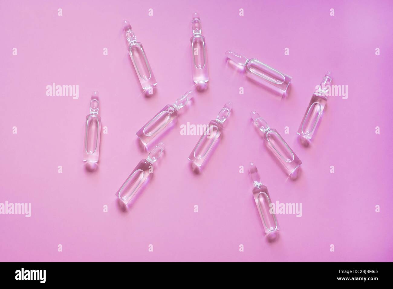 Ampoules with medicine on pink background. Pharmaceutical, cure. Stock Photo