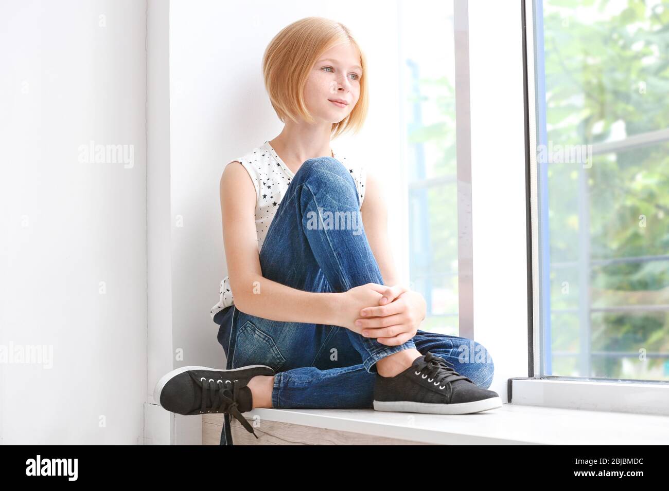 Cute teenager girl sitting near window Stock Photo