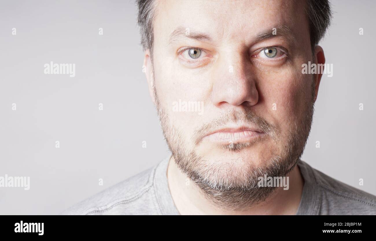 mid adult man looking at camera - close crop headshot with copy space on gray background Stock Photo