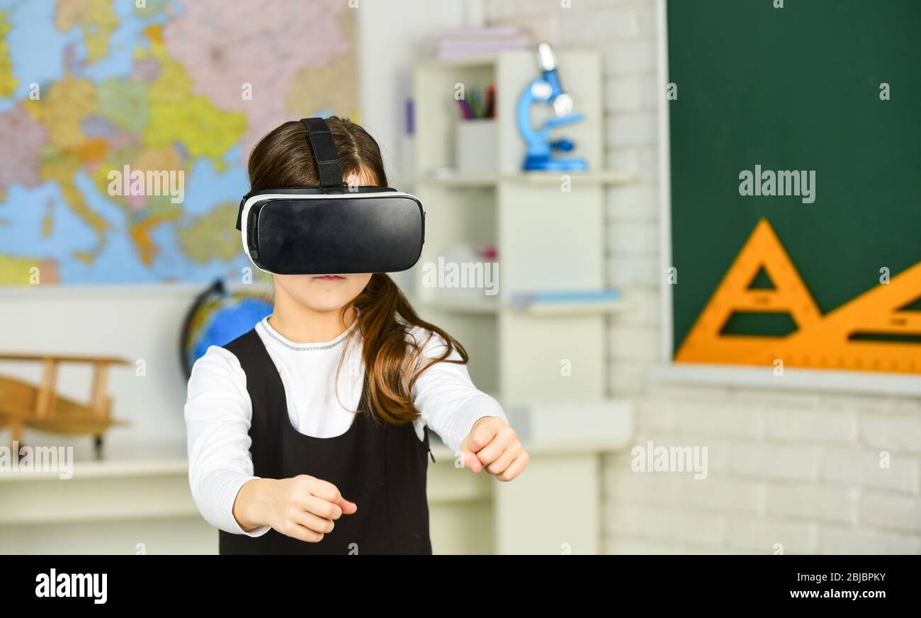 Go around obstacles. Virtual classes. Driving lessons. Science Class. VR technology. schoolgirl using virtual reality helmet. Virtual reality headset. Teenager student girl in classroom. Play game. Stock Photo