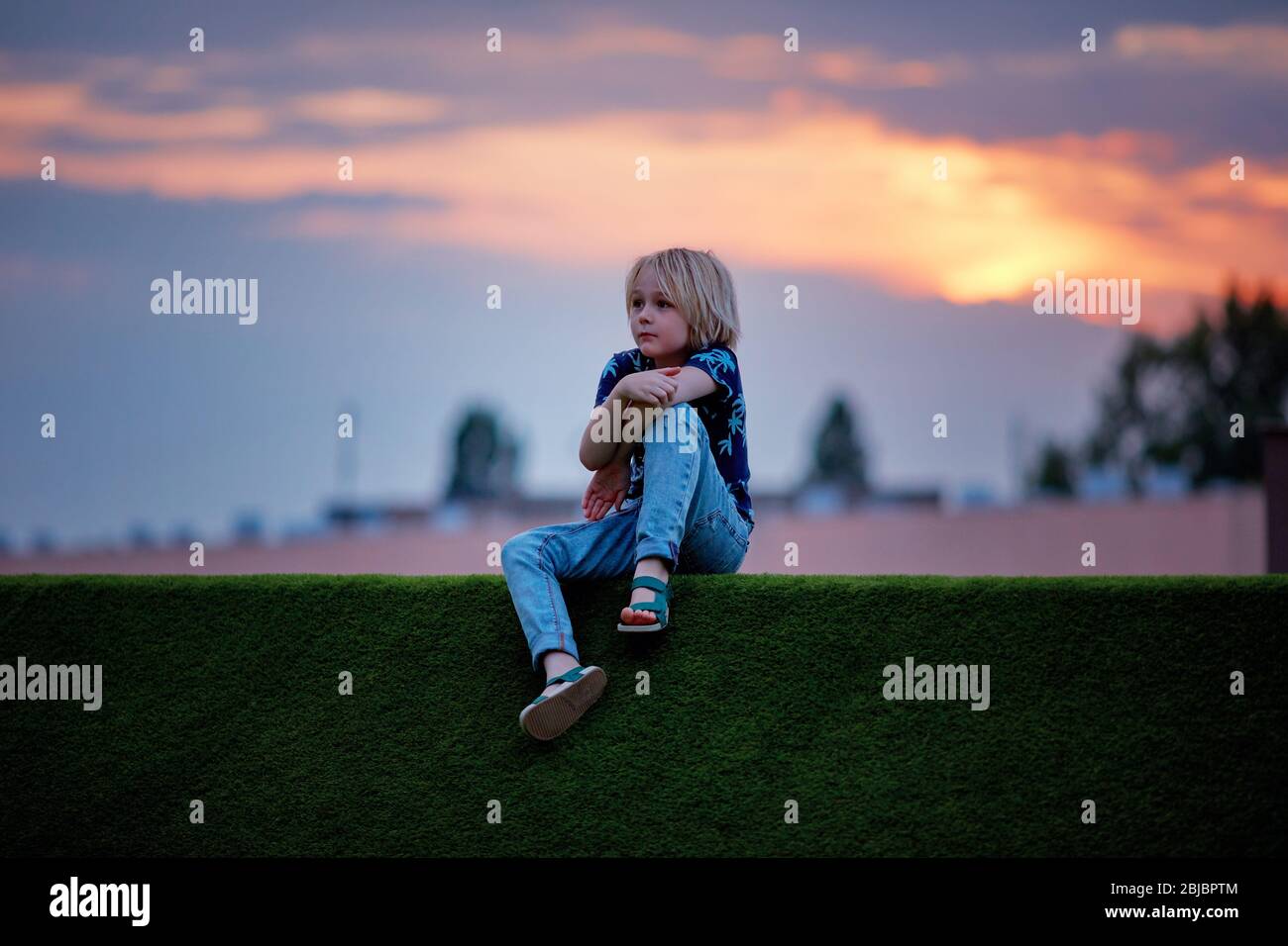 cute, nine year old boy in thoughts over the sunset skies Stock Photo