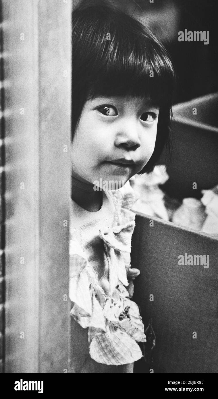 Hong Kong October 1986 A little girl peers out from her parents shop front in Sai Kung. The picture is is part of a collection of photographs taken in Hong Kong between September and November, 1986. They represent a snapshot of Daily Life in the Crown Colony eleven years before sovereignty was transferred back to mainland China. Photograph by Howard Walker / Alamy. Stock Photo
