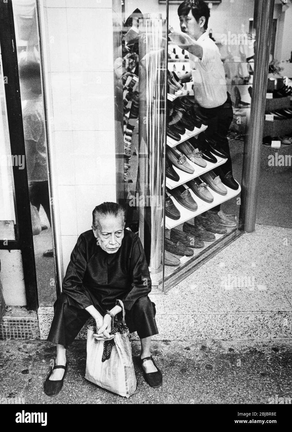 Hong Kong October 1986 An elderly woman rests on the shep of a shoe shop in Wan Chai. The picture is is part of a collection of photographs taken in Hong Kong between September and November, 1986. They represent a snapshot of Daily Life in the Crown Colony eleven years before sovereignty was transferred back to mainland China. Photograph by Howard Walker / Alamy. Stock Photo