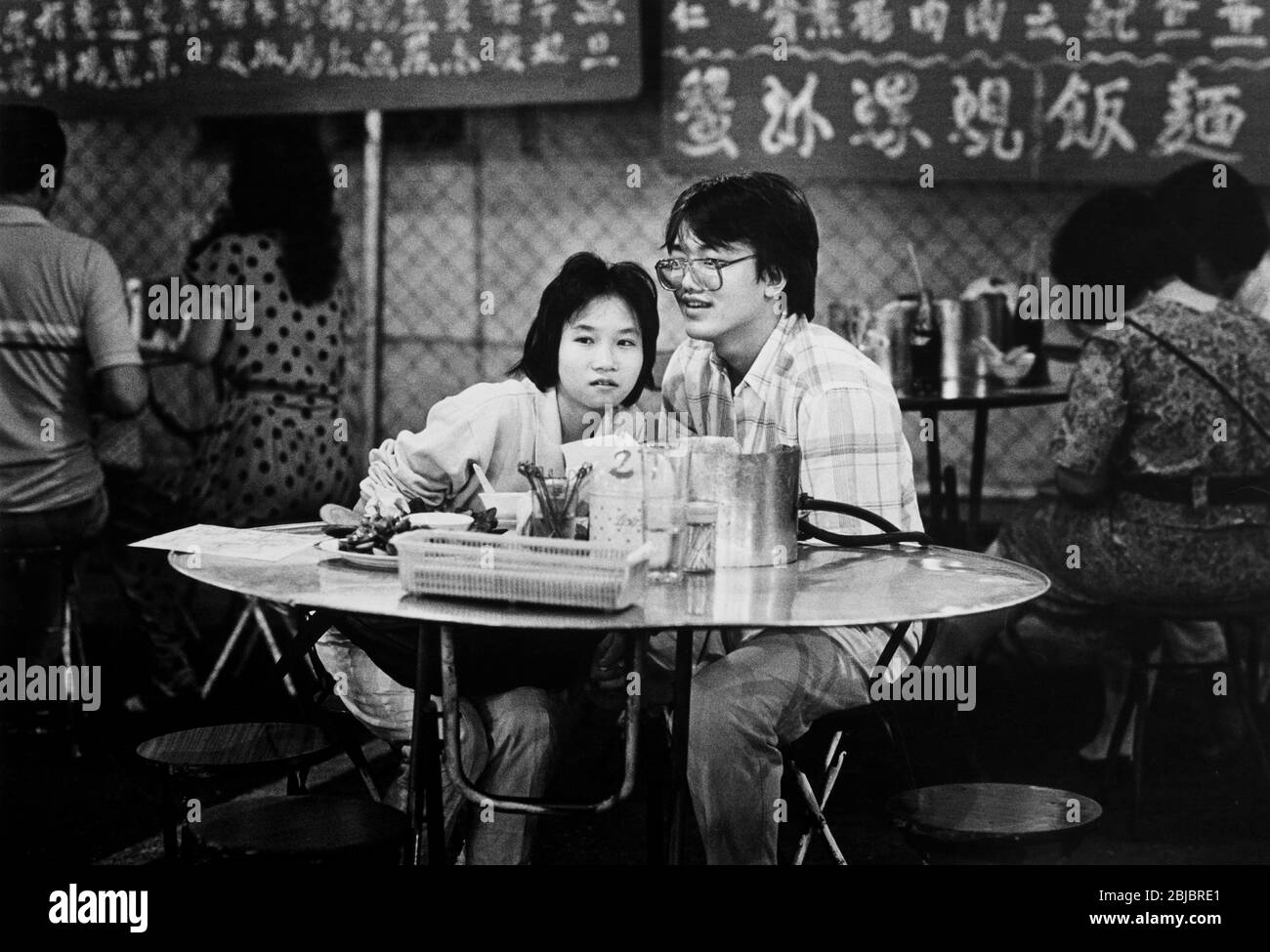 Hong Kong October 1986 A young couple wait for their meal at The Poor Man’s Nightclub in Mong Kok. The picture is is part of a collection of photographs taken in Hong Kong between September and November, 1986. They represent a snapshot of Daily Life in the Crown Colony eleven years before sovereignty was transferred back to mainland China. Photograph by Howard Walker / Alamy. Stock Photo