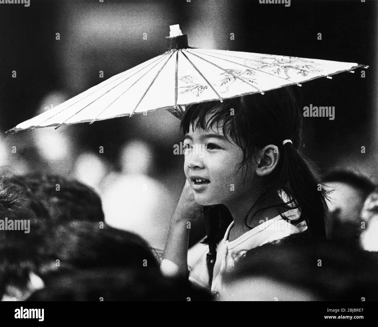 Hong Kong October 1986 A young girl waits in the crowd for the arrival of Queen Elizabeth II of Great Britainas she arrives at Victoria Harbour. The picture is is part of a collection of photographs taken in Hong Kong between September and November, 1986. They represent a snapshot of Daily Life in the Crown Colony eleven years before sovereignty was transferred back to mainland China. Photograph by Howard Walker / Alamy. Stock Photo