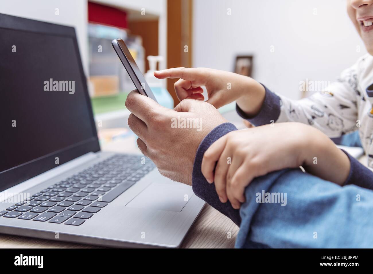 detail of a child hands bothering his father while working at home with his  smartphone and computer, work at home concept due to the coronavirus pande  Stock Photo - Alamy
