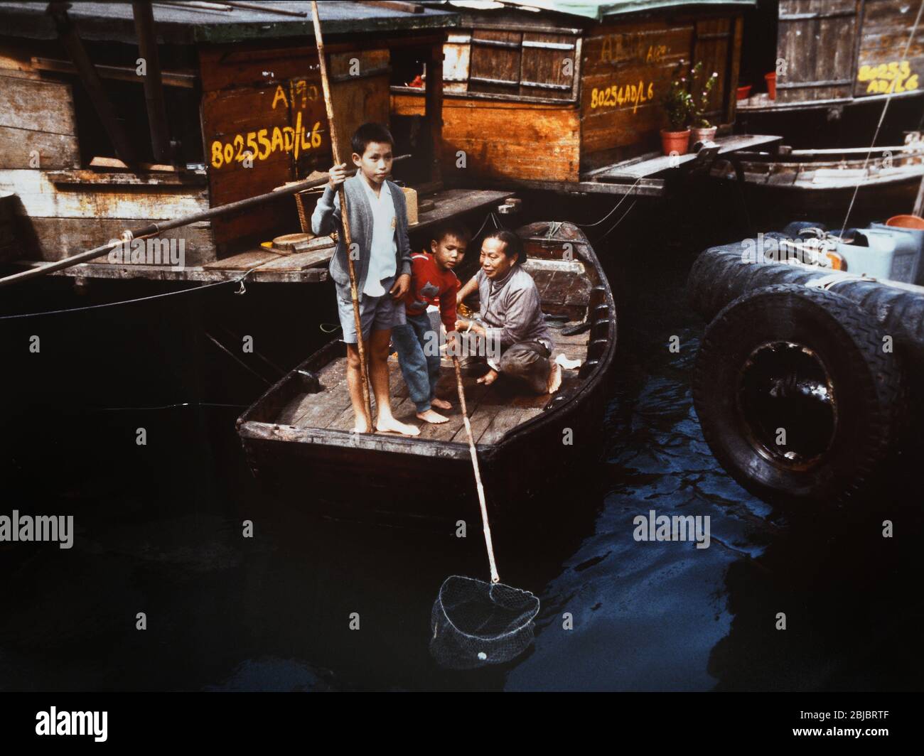 Hong Kong October 1986 Boat children in Aberdeen Harbour catch money from passing boats. The picture is is part of a collection of photographs taken in Hong Kong between September and November, 1986. They represent a snapshot of Daily Life in the Crown Colony eleven years before sovereignty was transferred back to mainland China. Photograph by Howard Walker / Alamy. Stock Photo