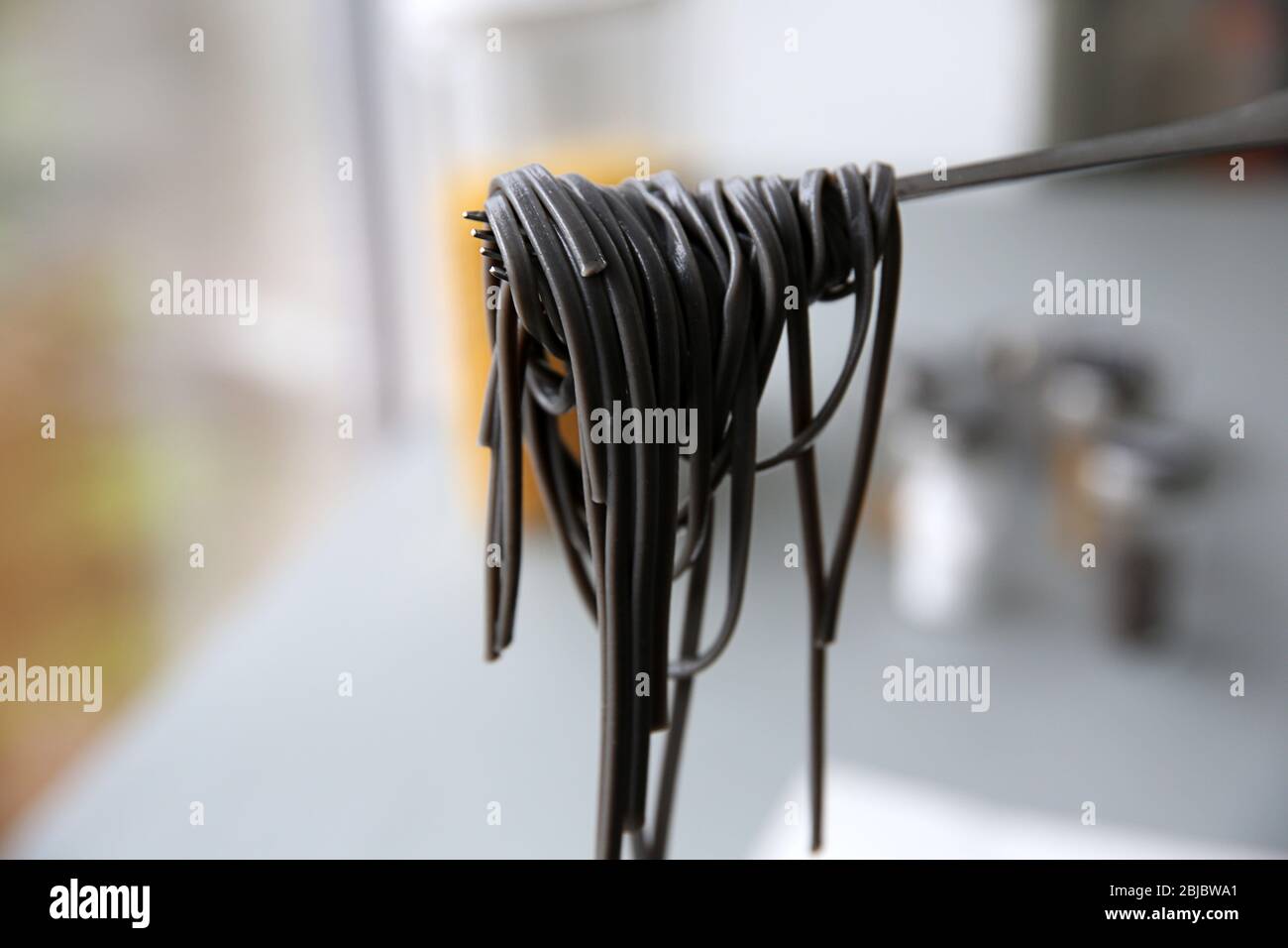 Black pasta on fork in kitchen Stock Photo