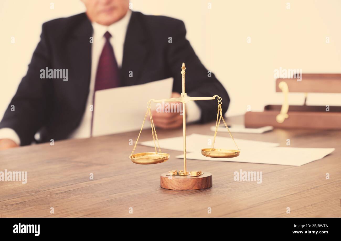 Scales of justice on wooden table and male lawyer on background Stock ...