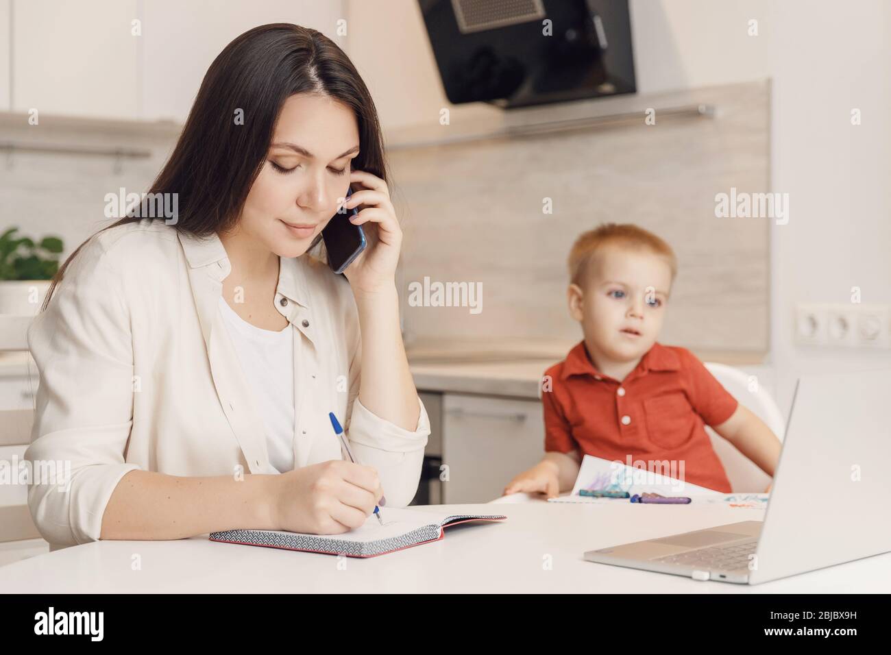 Businesswoman mother woman with kid working online computer and call phone home office Stock Photo