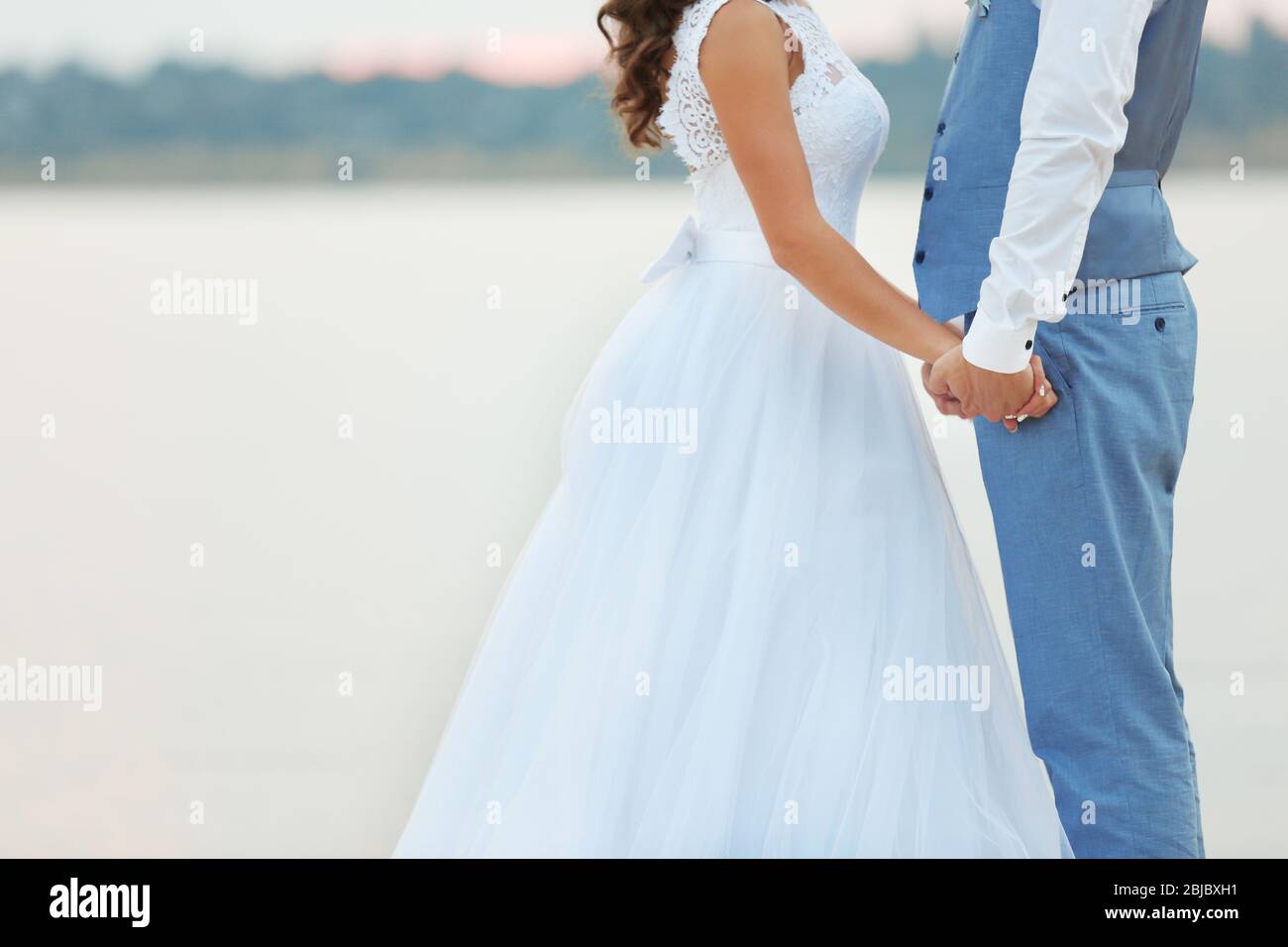 Beautiful wedding couple holding hands near river, close up view Stock ...