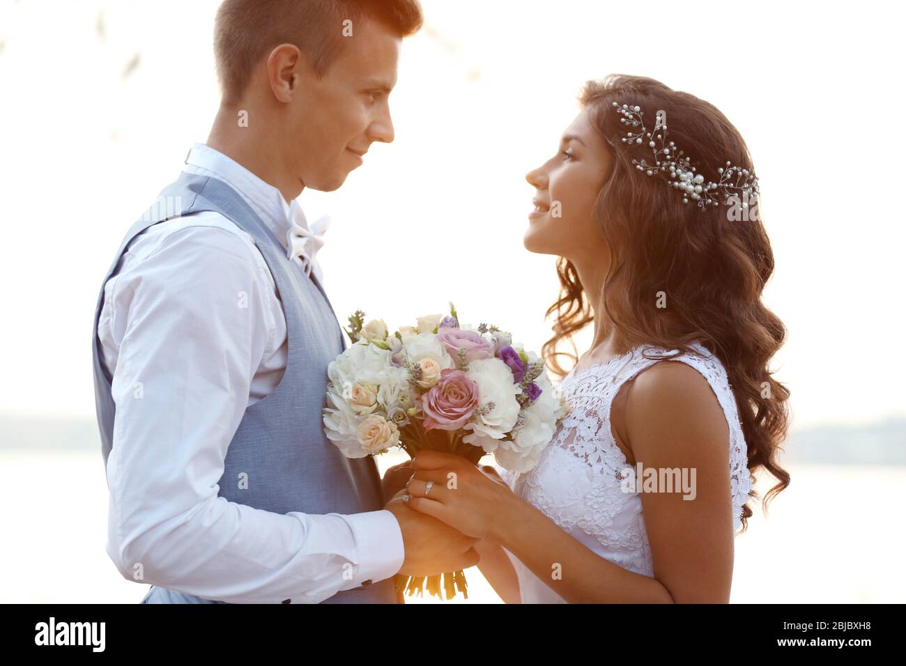 Portrait of beautiful wedding couple outdoors on light blurred background Stock Photo