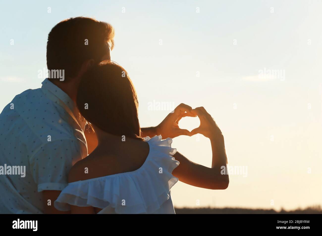Young couple making heart with their hands on beach Stock Photo - Alamy