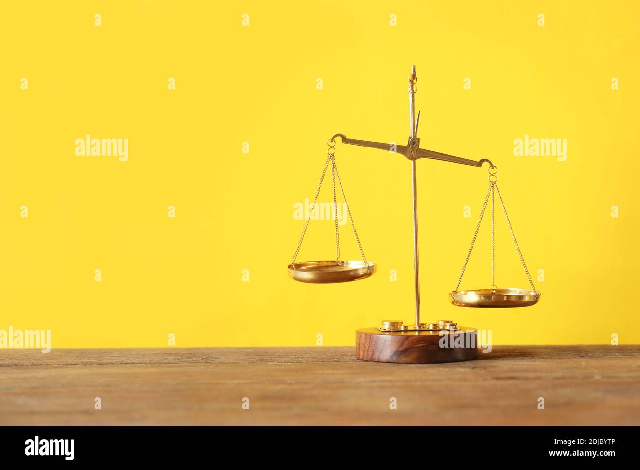 Justice scales on wooden table and yellow background Stock Photo - Alamy