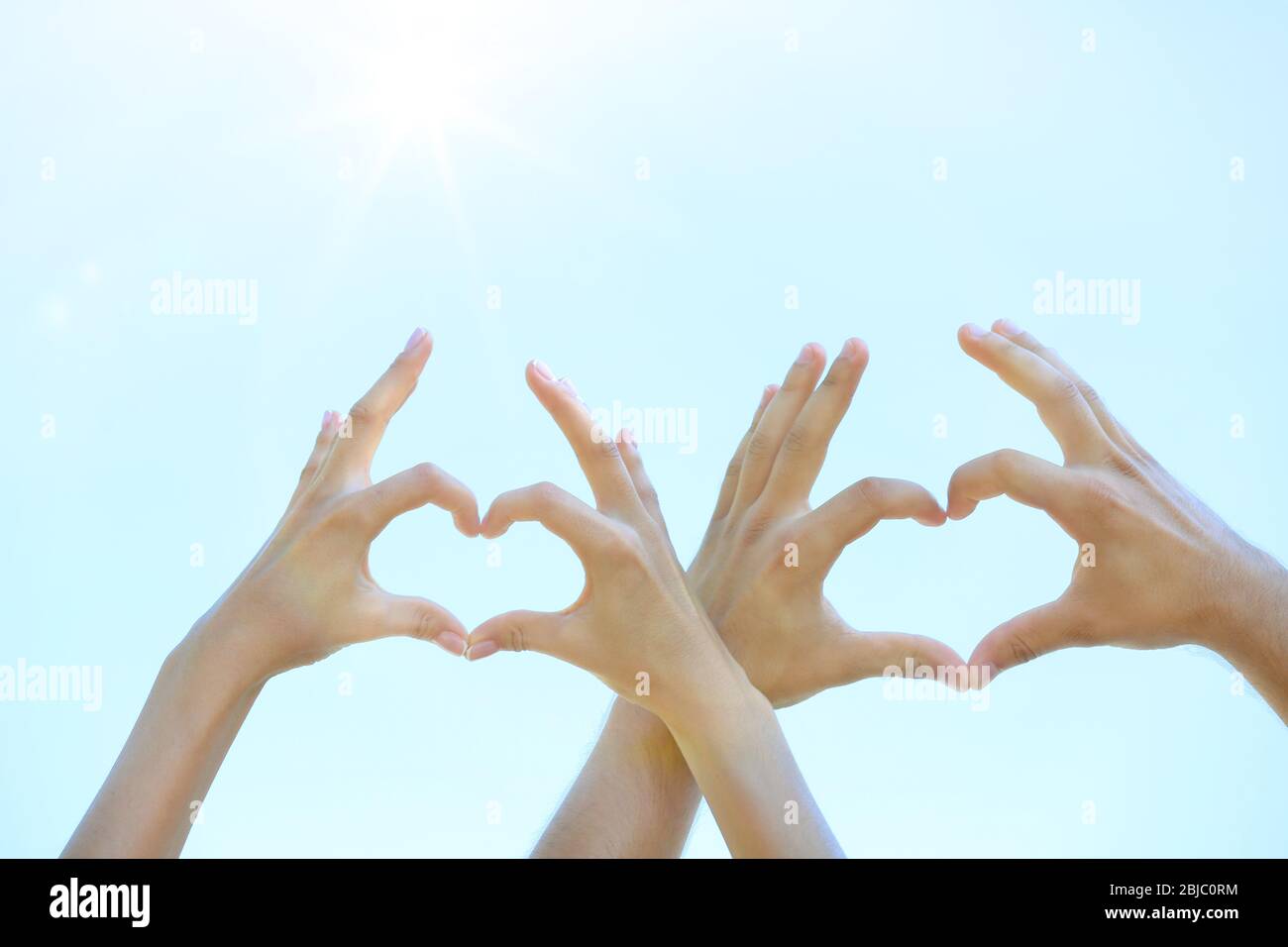 Couple making heart shape with hands on blue sky background Stock Photo ...