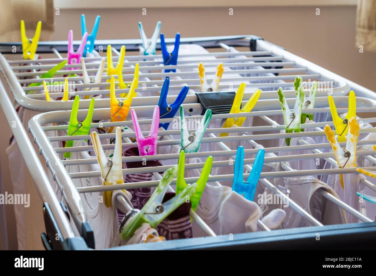 Clothes drying on rack fixed with colourful plastic pegs pins Stock Photo
