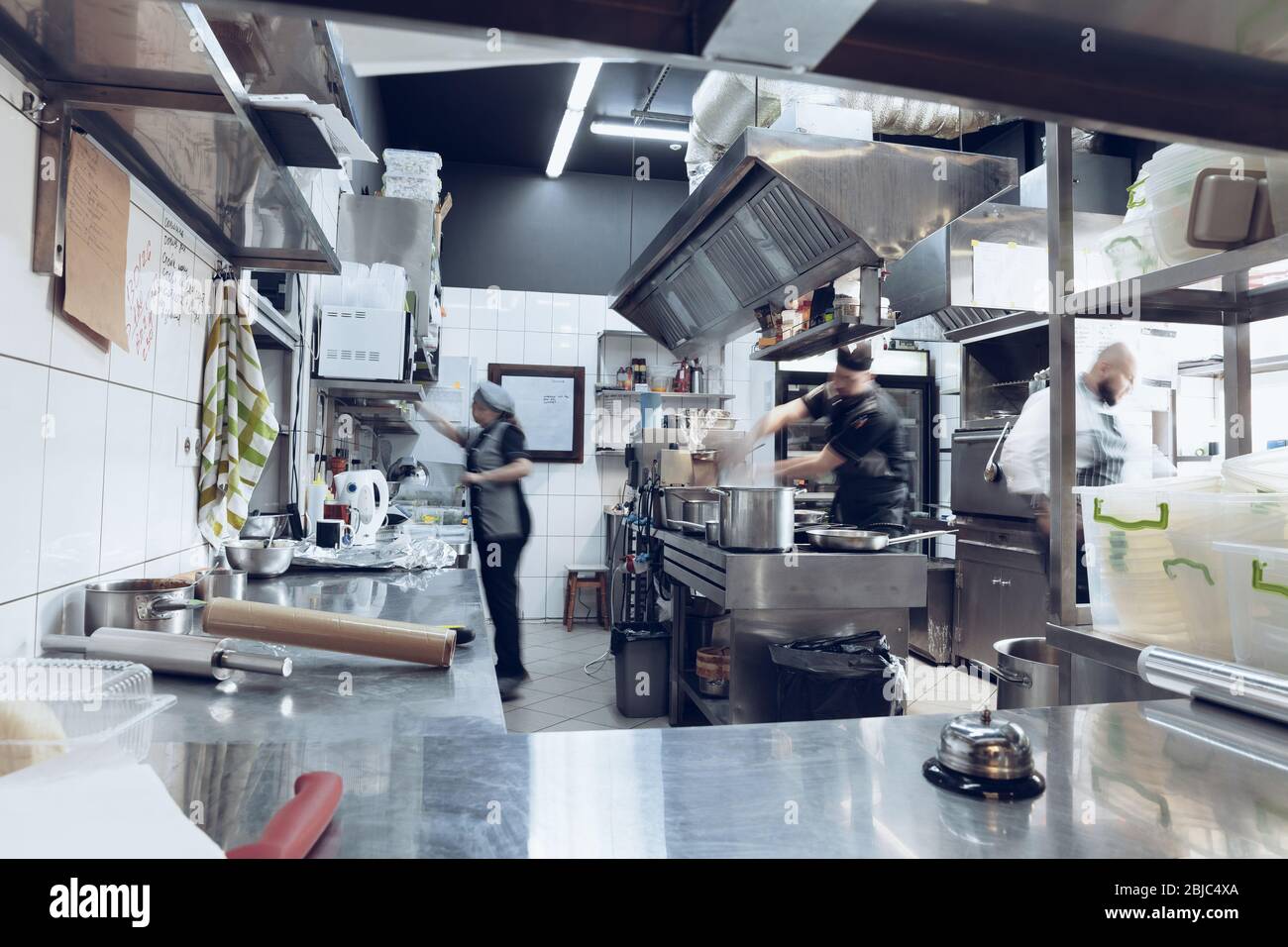 Behind the scenes of brands. The chef cooking in a professional kitchen of a restaurant meal for client or delivery. Open business from the inside. Meals during the quarantine. Hurrying up, motion. Stock Photo
