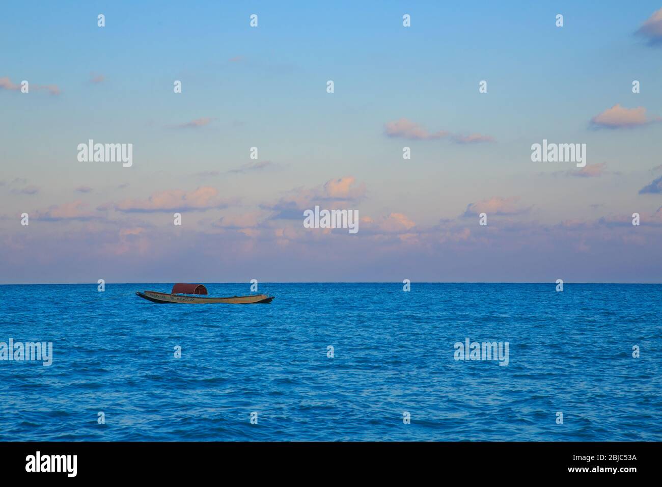 Beautiful view of a boat drifting in the blue water at the backdrop of colourful sky during sunset (Havelock, Island, Andaman, India) Stock Photo