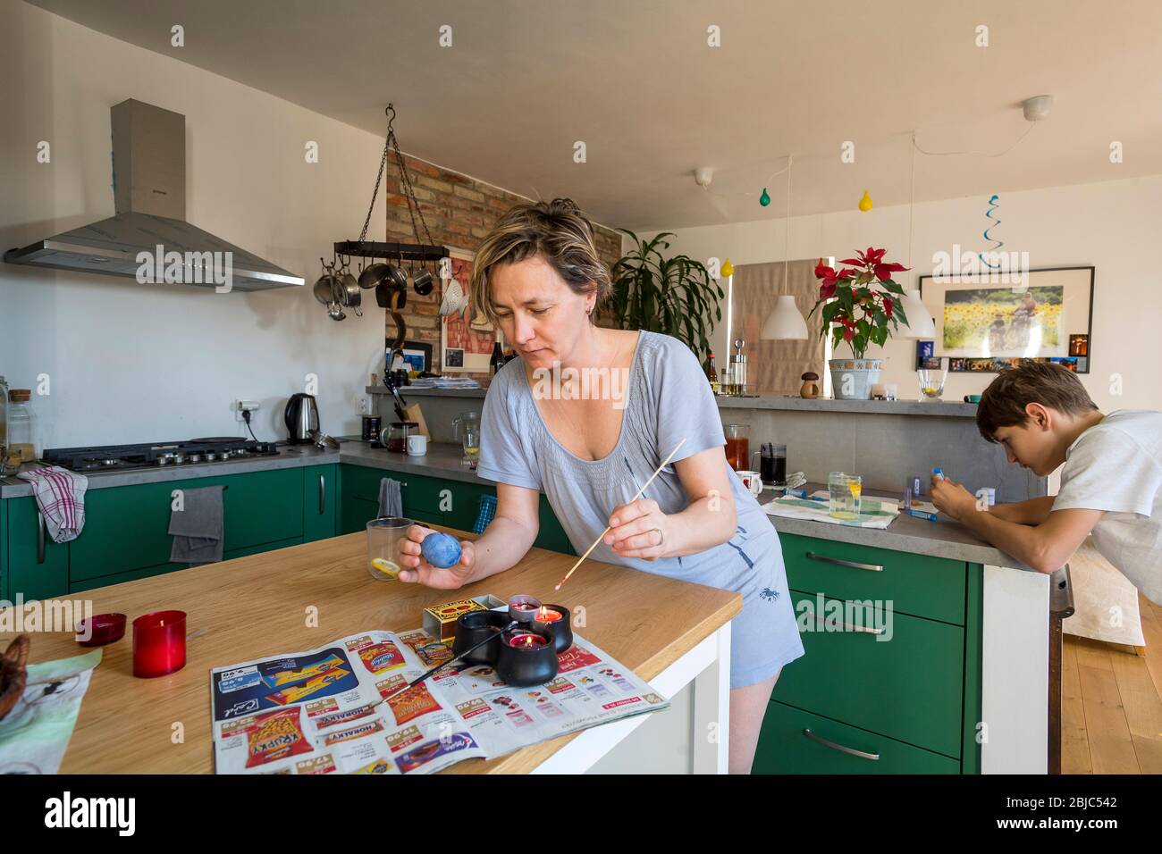 mother and son colouring Easter egg at home in the kitchen Stock Photo