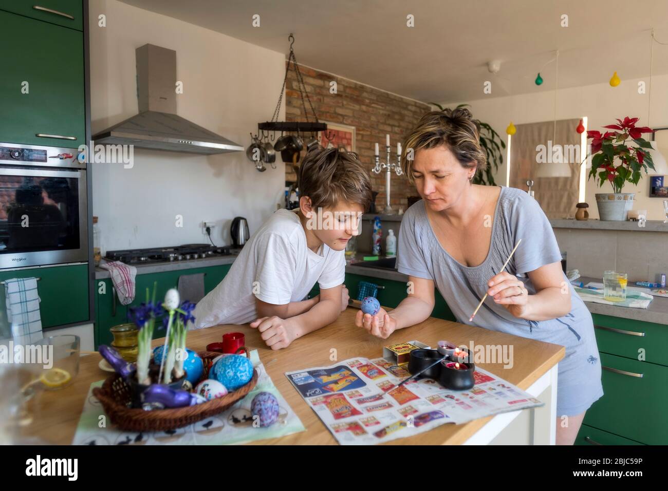 mother and son colouring Easter egg at home in the kitchen Stock Photo