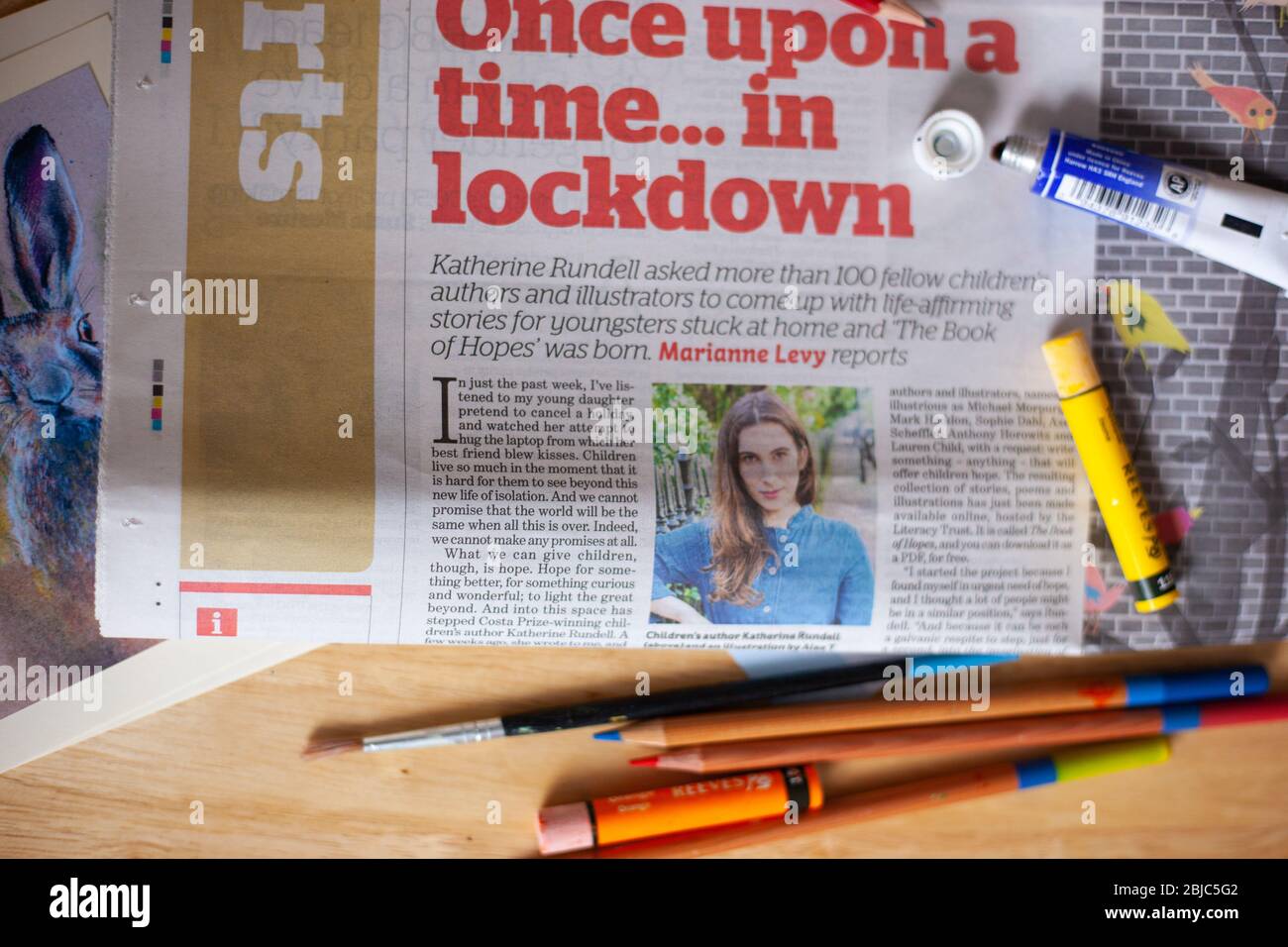 Arts & Culture News concept during Coronavirus lockdown. UK, April 2020. Arts in the News with art materials & newspaper on desk. Stock Photo