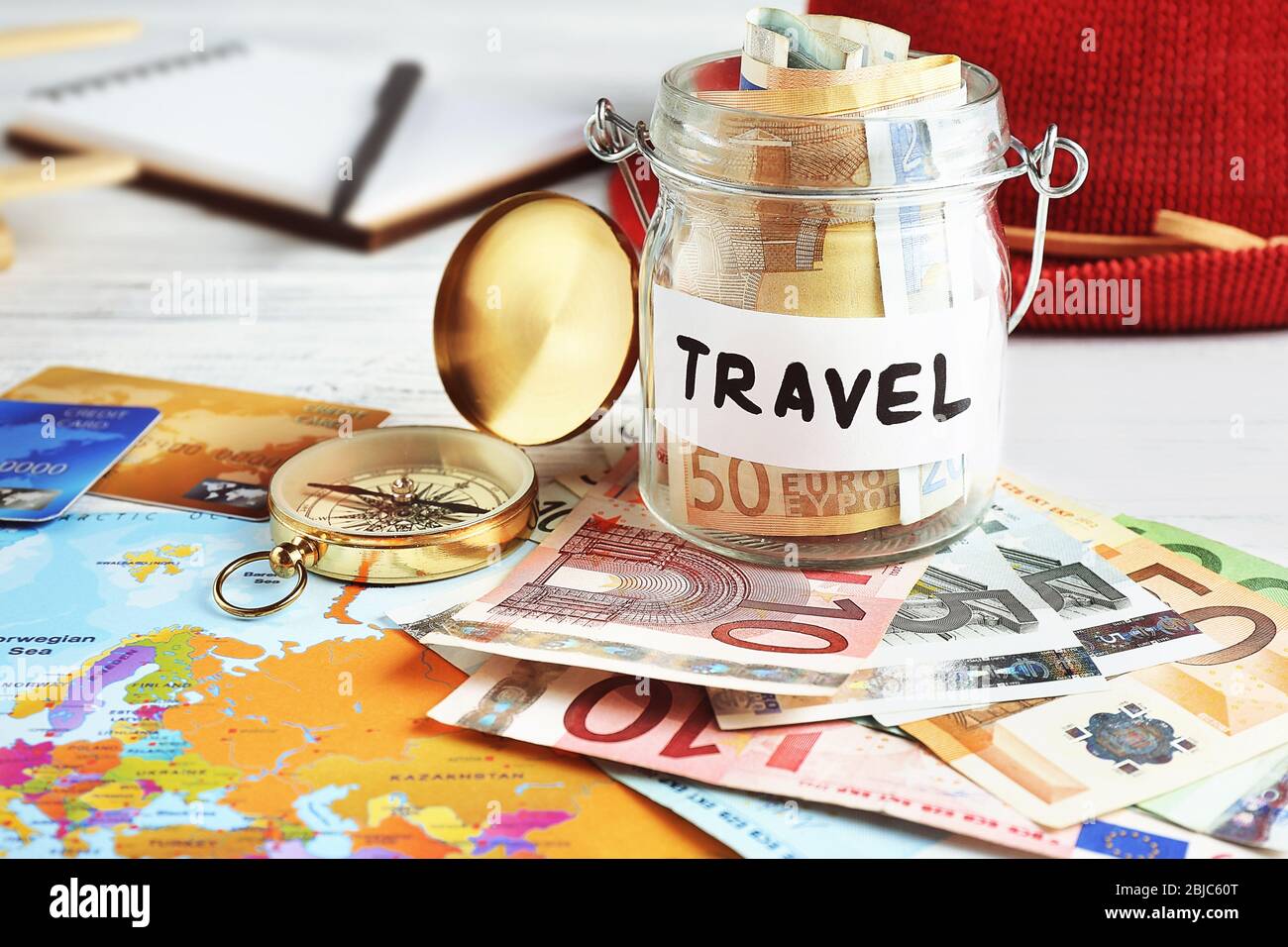 Travel money savings in a glass jar with compass, map and hat Stock Photo