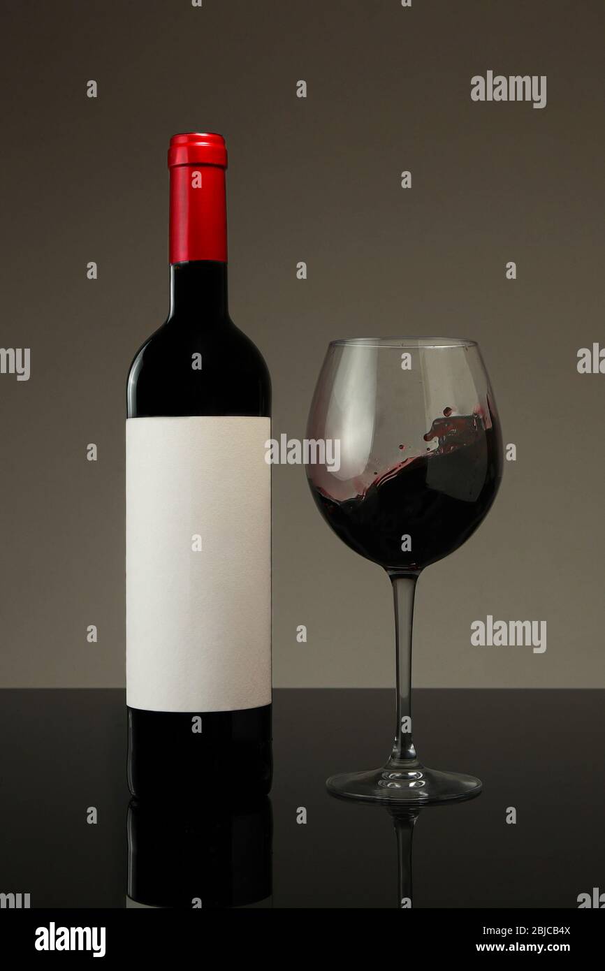 Bottle of red wine and glass with a neutral background Stock Photo