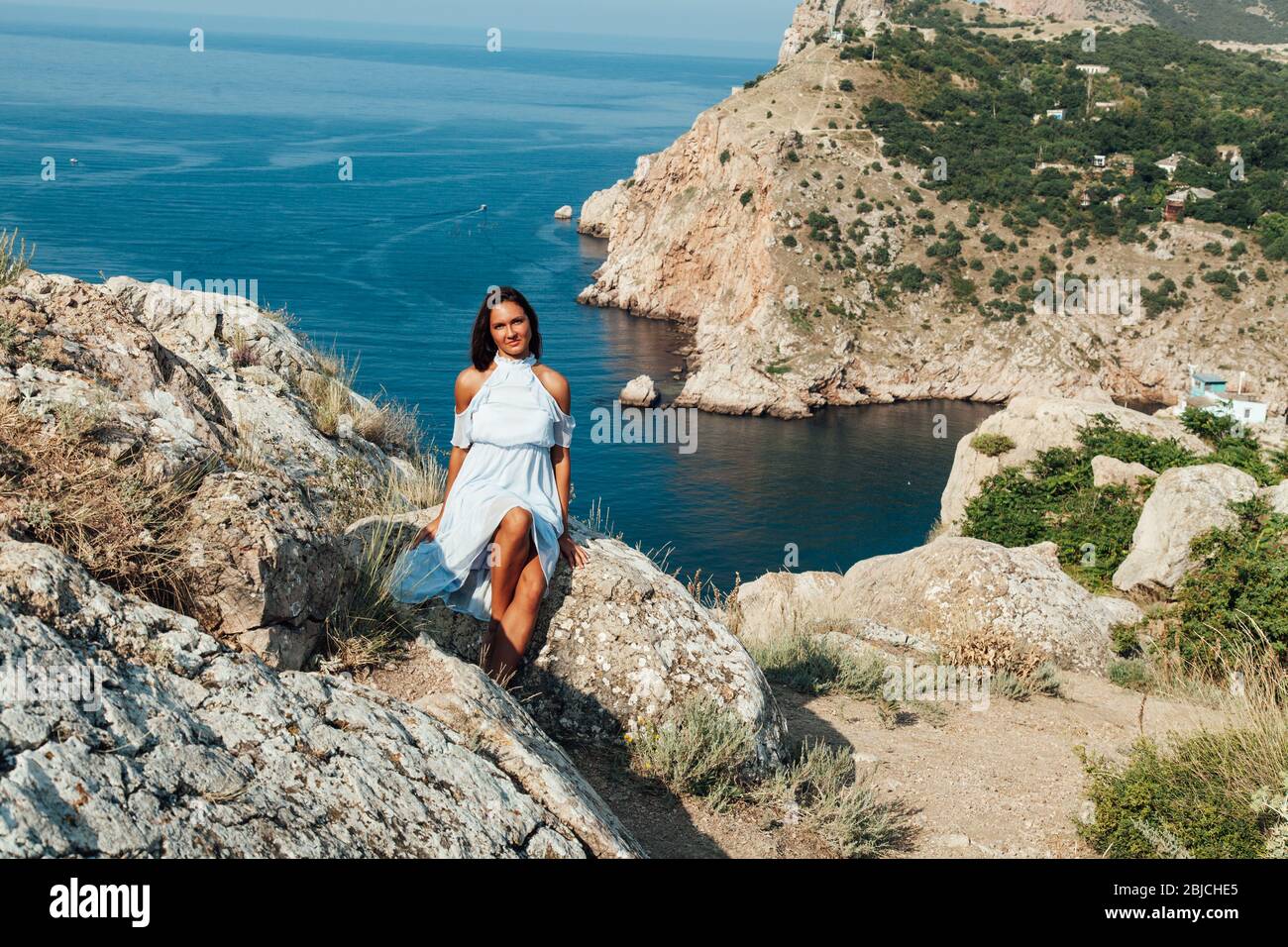 Beautiful woman in a dress with long hair travels a beautiful sea landscape Stock Photo