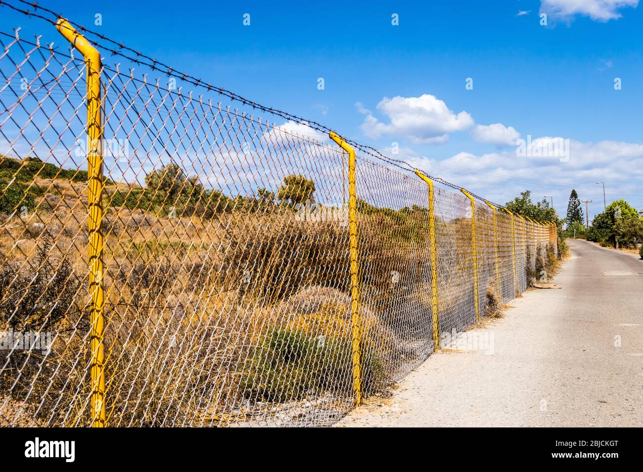 Industrial wire fence panels, metal fence panel and yellow stakes for a  hill in Crete Stock Photo - Alamy